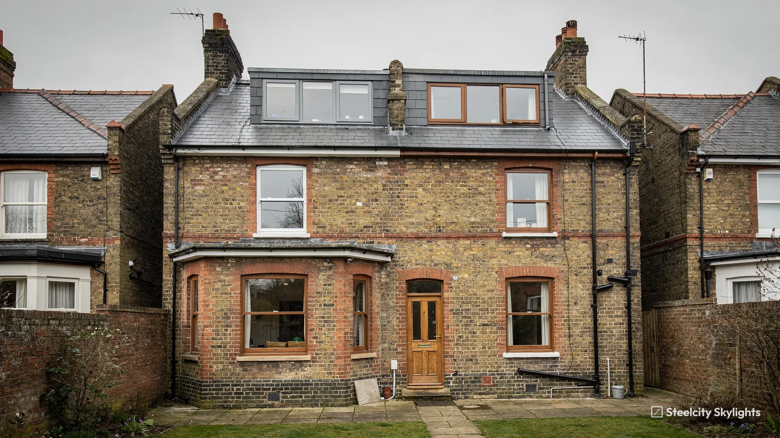 Rear of a yellow brick terraced house with a slate roof and a dormer loft conversion