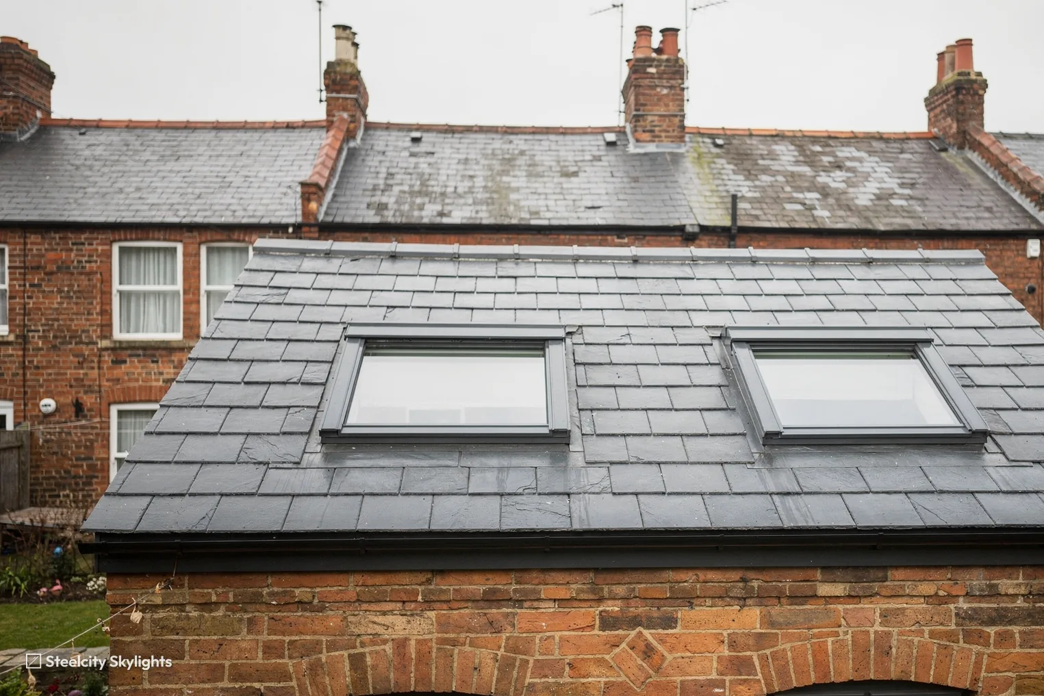 Two top-hung roof windows in the slate roof of the rear outshot on a brick terrace