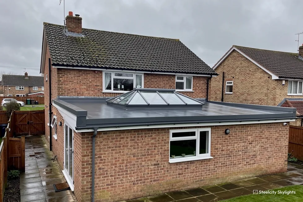 Brick house with an L-shaped single-storey extension and a hipped roof lantern on its flat roof