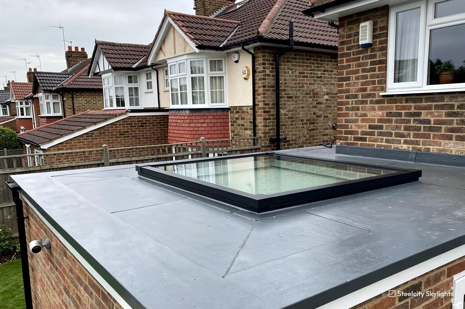 Fixed flat rooflight on the grey single-ply roof of a brick extension, semis behind