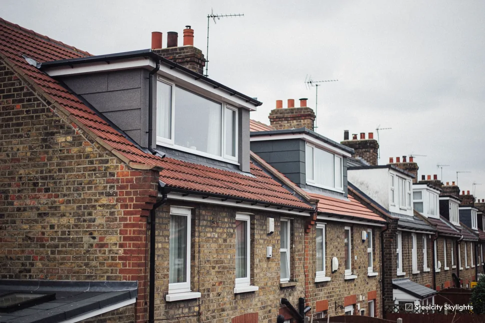 Row of brick terraced houses with box dormer loft conversions in the tile roofs