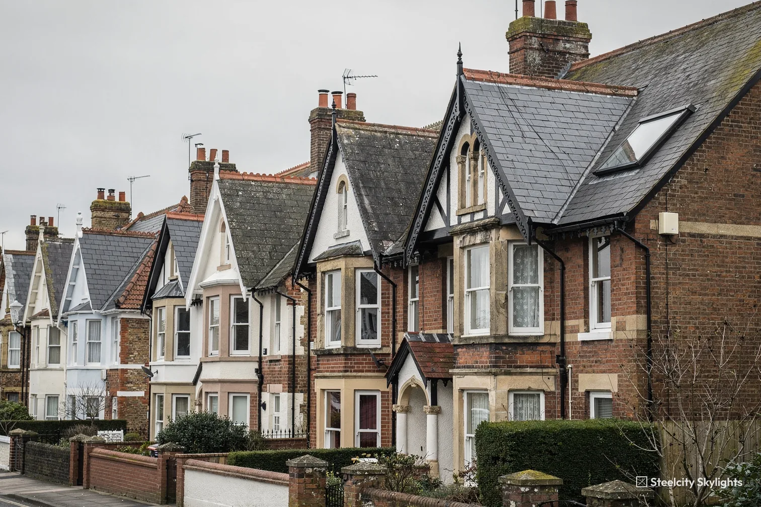 Row of gabled brick and stone villas with decorative bargeboards and a roof window in the slate