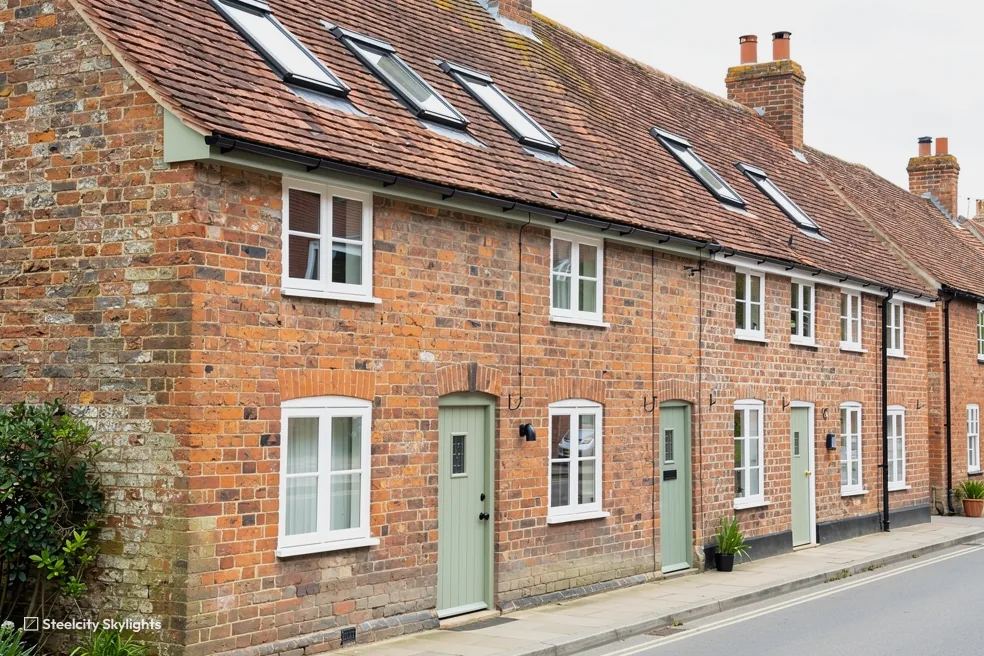 Row of brick terraced cottages with several roof windows in the clay tile roof