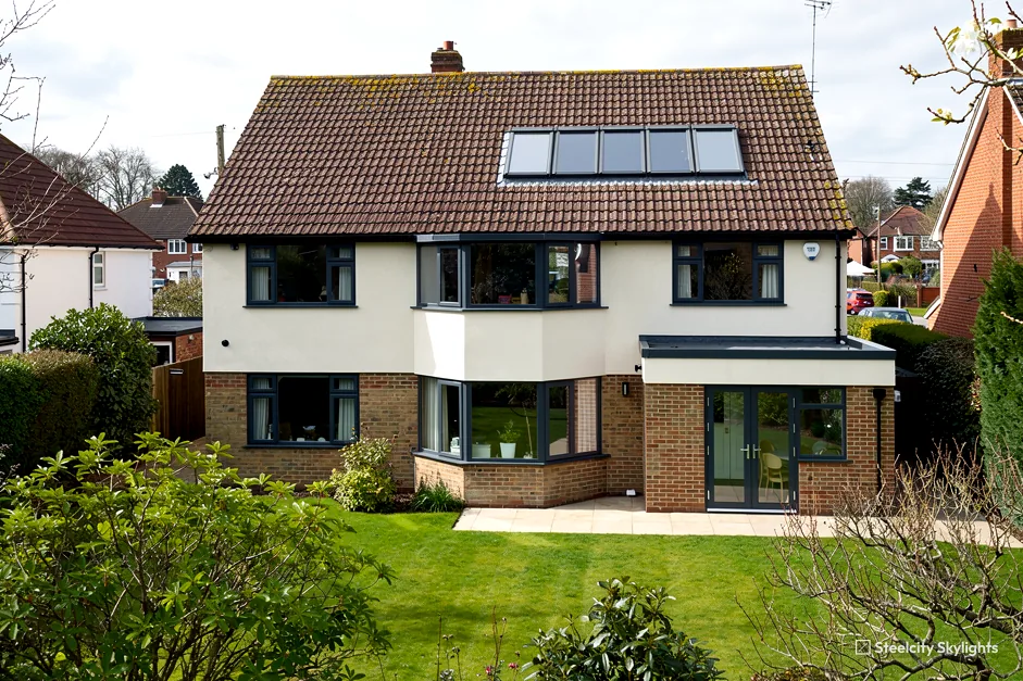 Detached house with four roof windows in its tile roof and a rendered upper storey