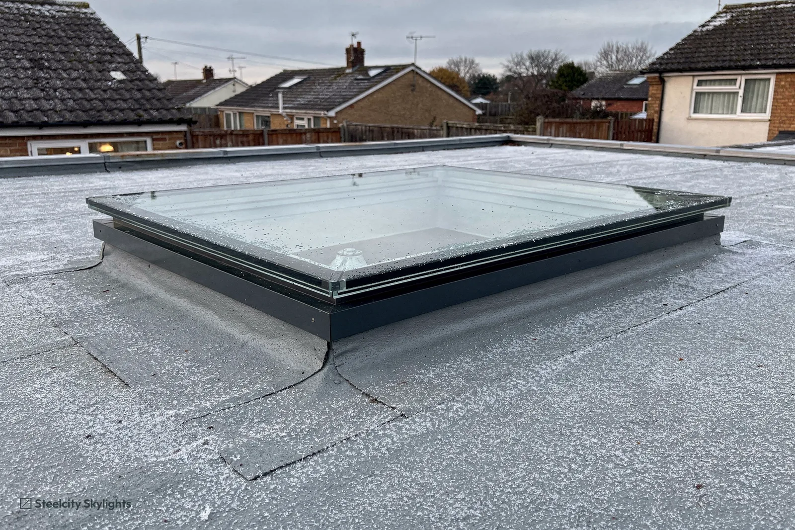 Fixed flat rooflight with a grey frame on a grey single-ply flat roof