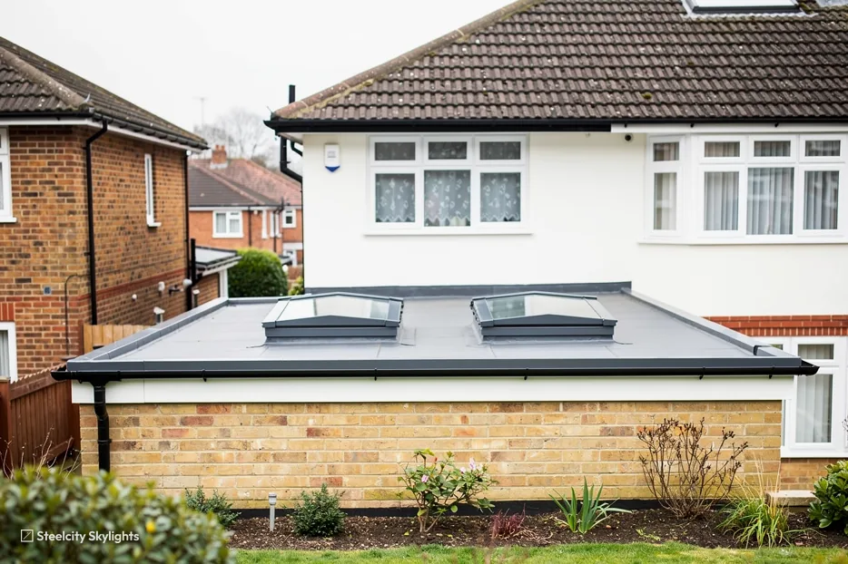 Two matching flat rooflights on the roof of a brick extension behind a rendered semi