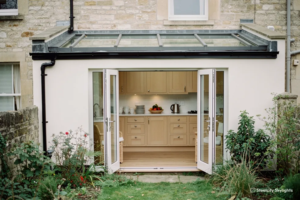 Stone terraced house with a white rendered rear extension, glazed roof and open French doors to a kitchen
