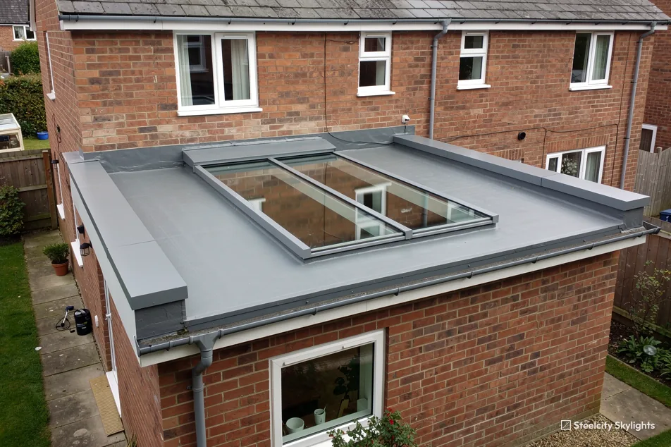 Three-pane flat rooflight on the grey roof of a brick rear extension, seen from above