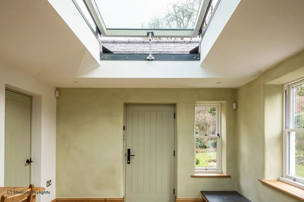 Entrance hall with a painted plank door, lit by an opening rooflight raised in the ceiling