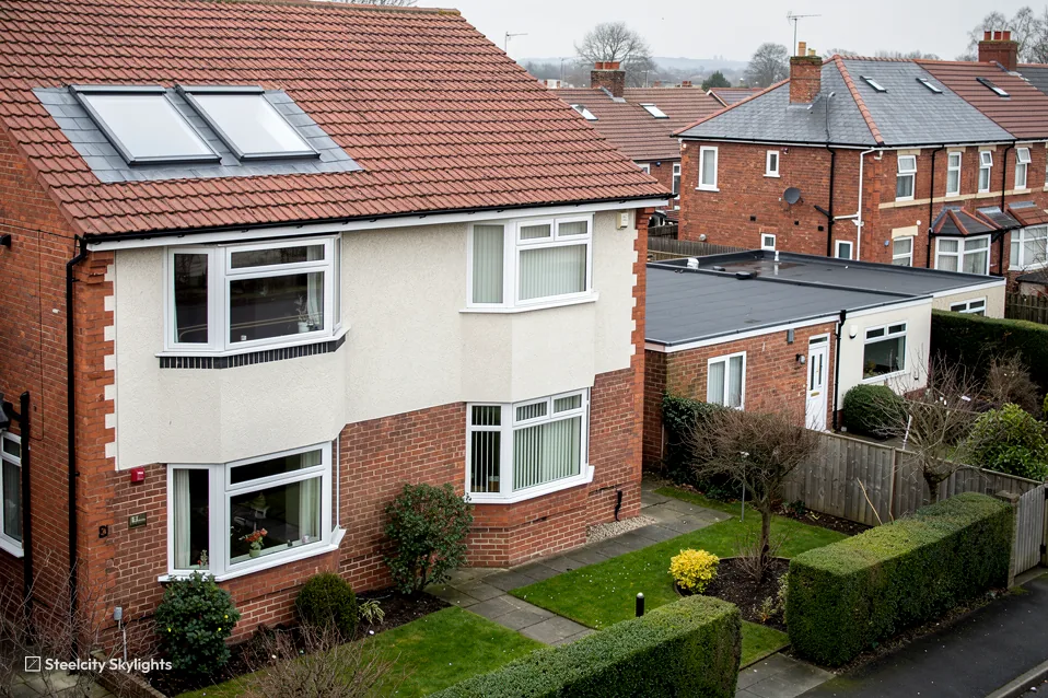 Semi-detached house with two roof windows in its tile roof, seen from above the front garden